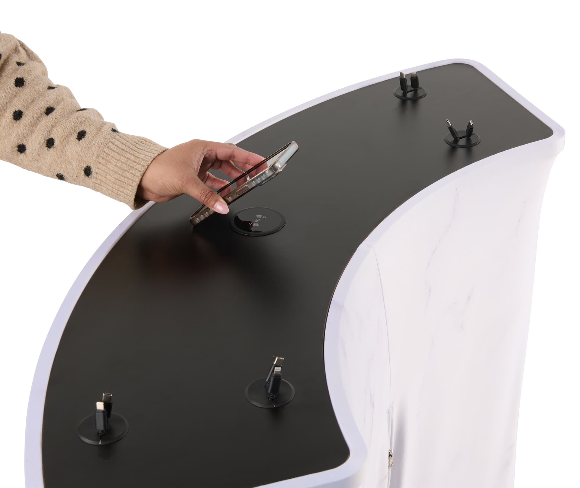 Trade show charging station with a wireless charging pad in the middle of the table and an individual placing a phone on it