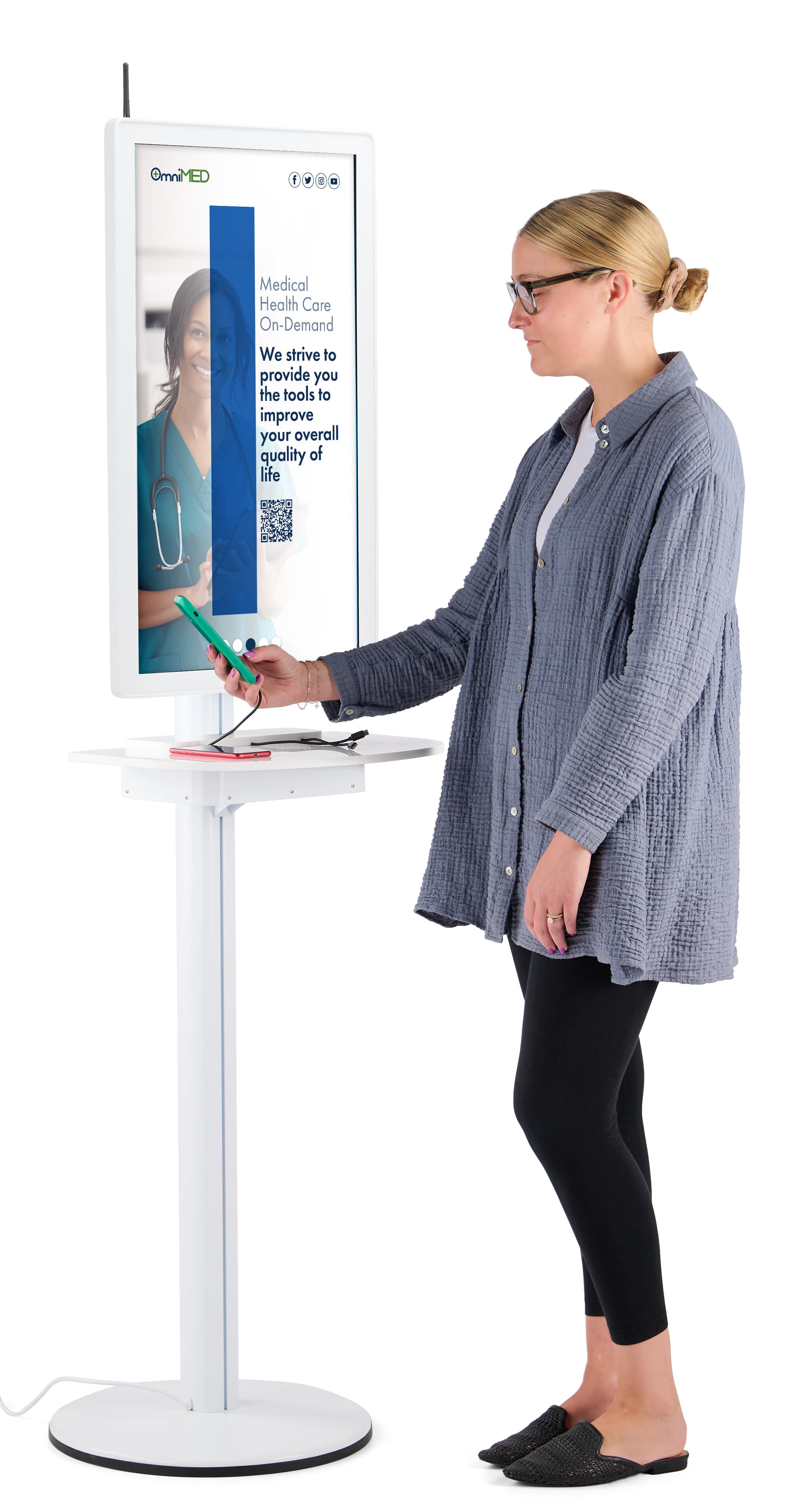 Digital charging station with an individual interacting with charging kiosk checking the charge of her phone while an advertisement for a healthcare facility plays on the screen