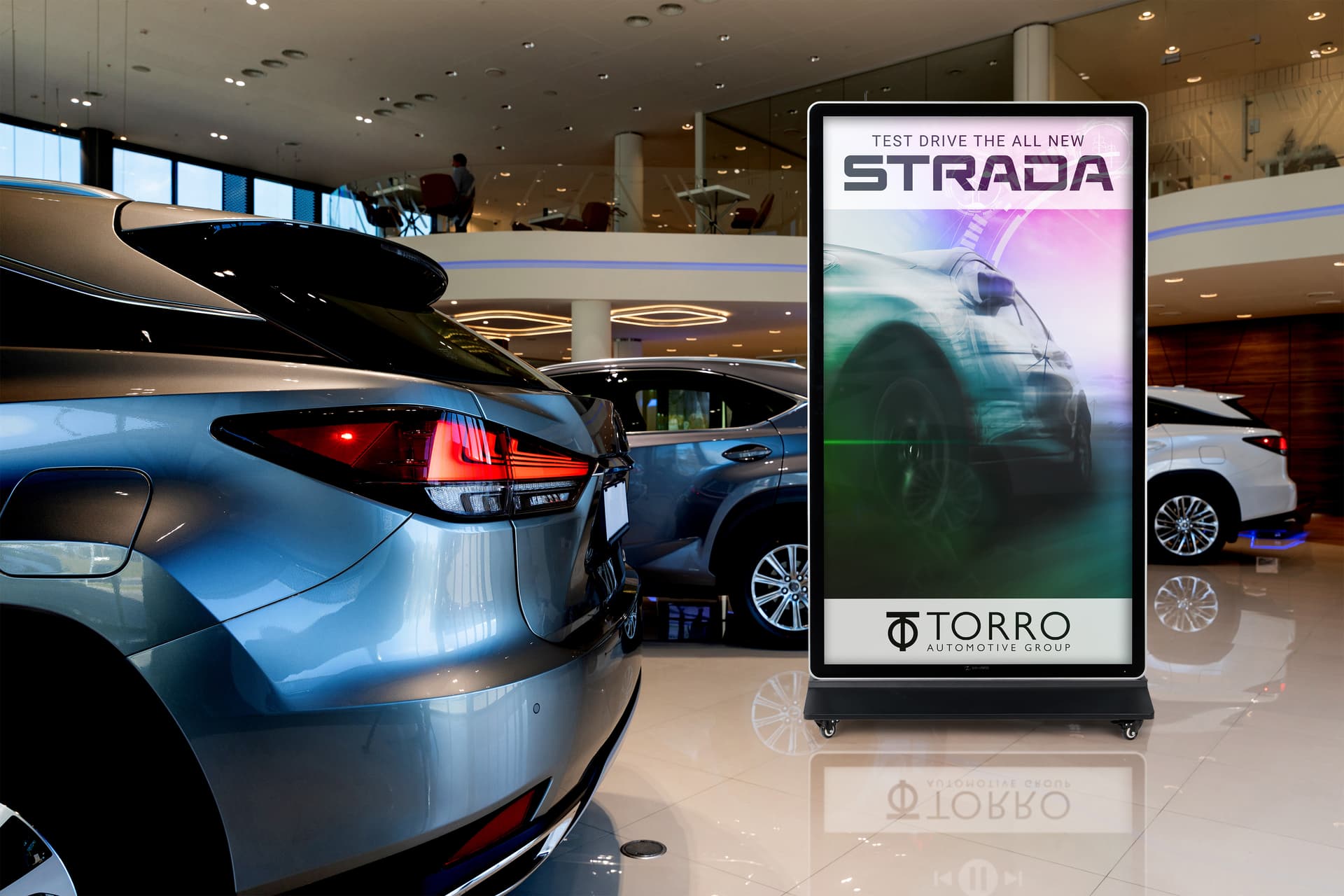Digital display advertising floor stand showcasing the unit in a car showroom playing a video of a car advertisement
