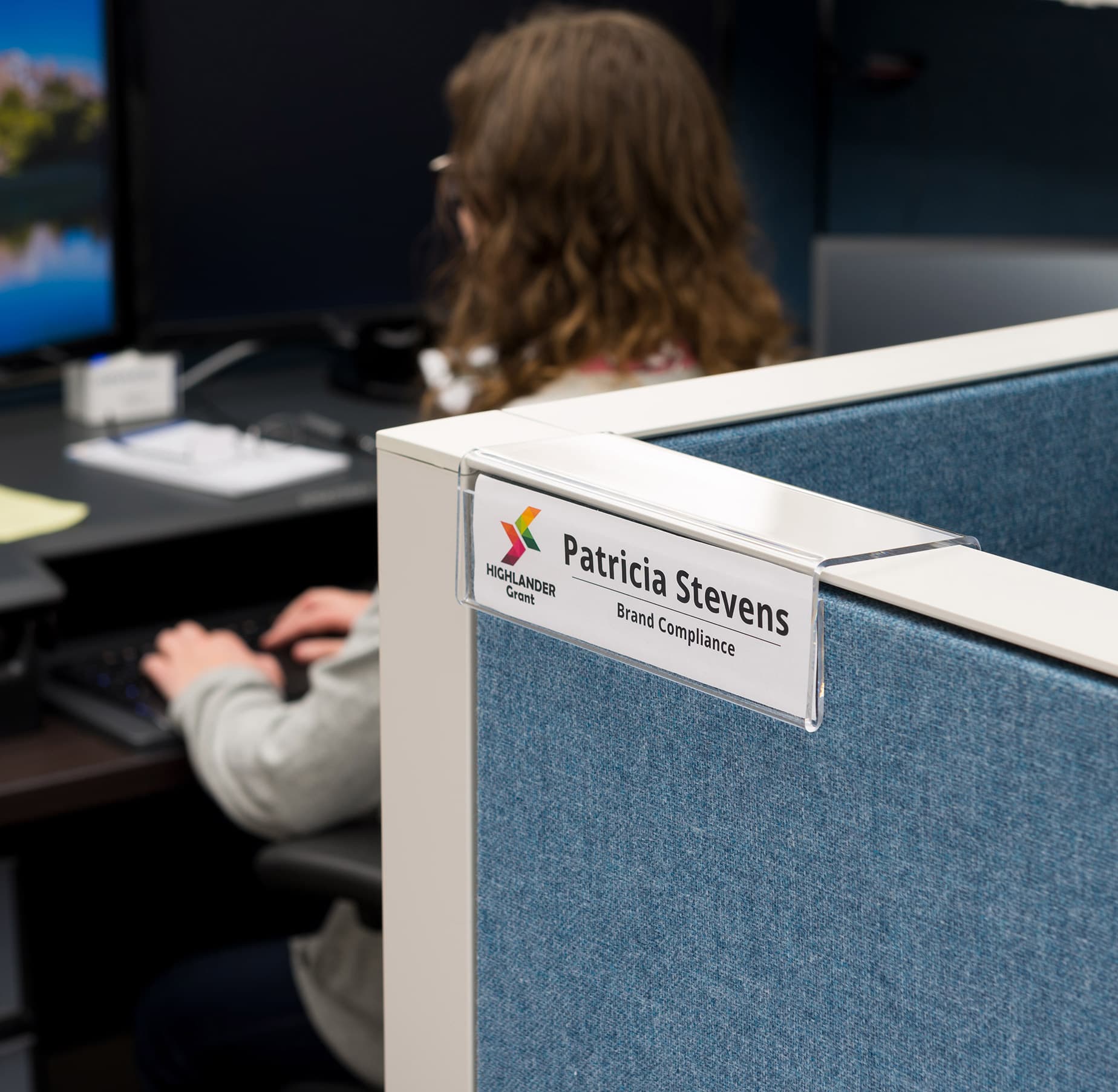 Acrylic cubicle name plate bracket shown in office setting
