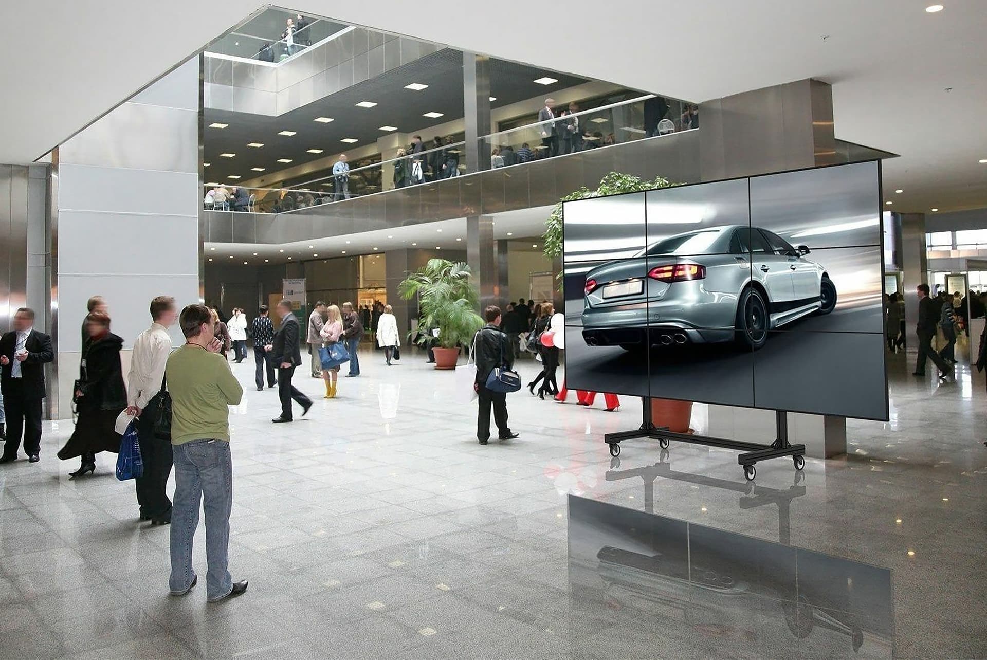 Portable video wall cart showcasing the stand being utilized with a three by three video wall configuration displaying a car advertisement in a mall setting