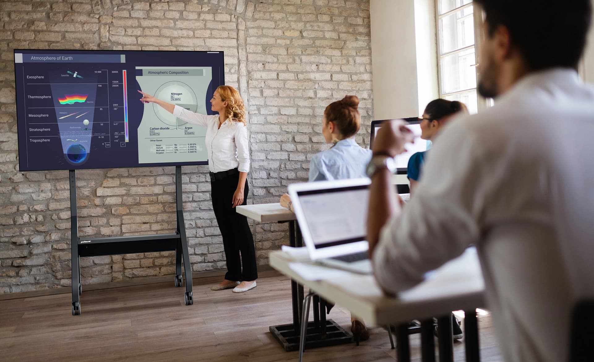 Rolling flat panel TV cart being used in a higher education setting during a presentation